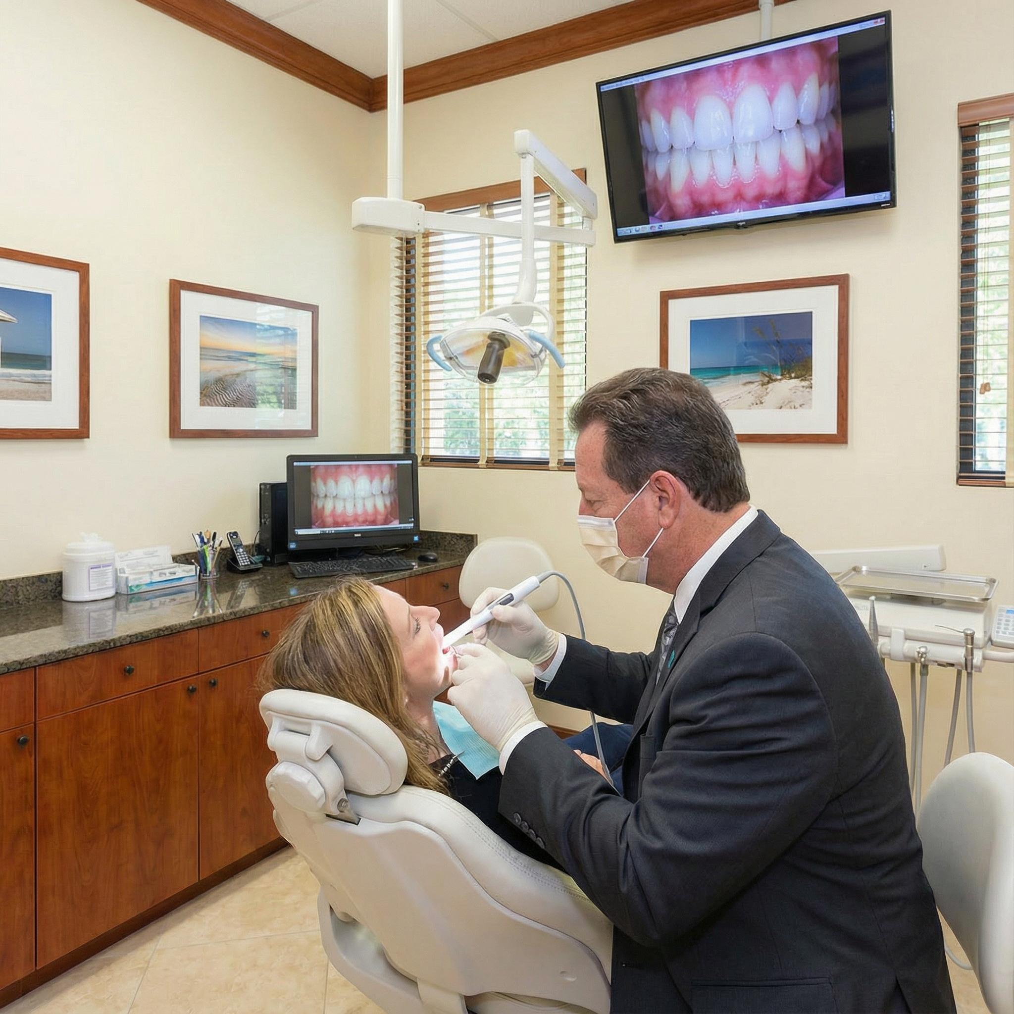 Dr. Eggnatz using intra oral camera with patient, showing dental images on monitor